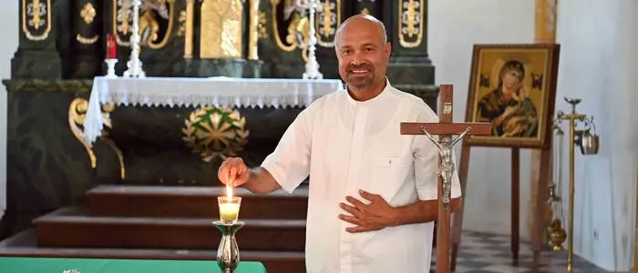 Ein Priester steht vor einem Altar und zündet eine Kerze an.