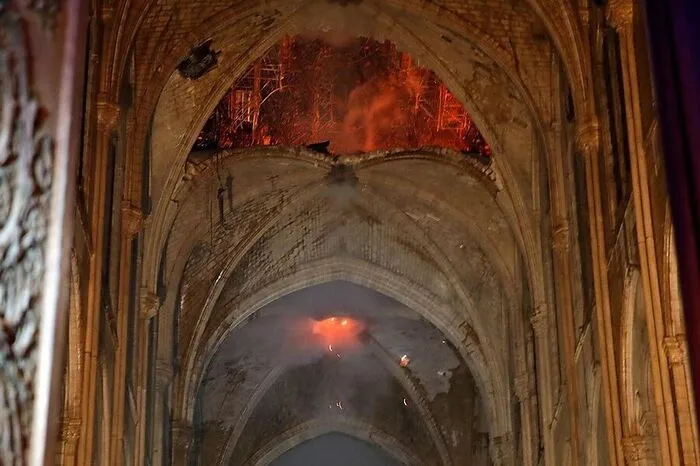 Flammen lodern durch das eingestürzte Dach der Kathedrale.