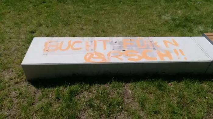 Die hölzernen Sitzgelegenheiten wurden abgerissen, darunter bleibt nur der blanke Beton. Dafür mit einem obszönen Spruch "verziert".
