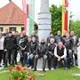 Eine Gruppe Motorradfahrer posiert vor einer Säule