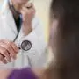 Eine Ärztin untersucht mit einem Stethoskop einen Patienten