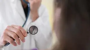 Eine Ärztin untersucht mit einem Stethoskop einen Patienten