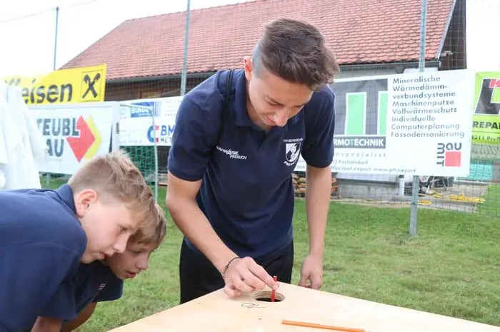 Beim Lochspiel war Geschicklichkeit gefragt. Über Löcher in einem Tisch mussten Stifte in verschieden große Behälter geworfen werden.