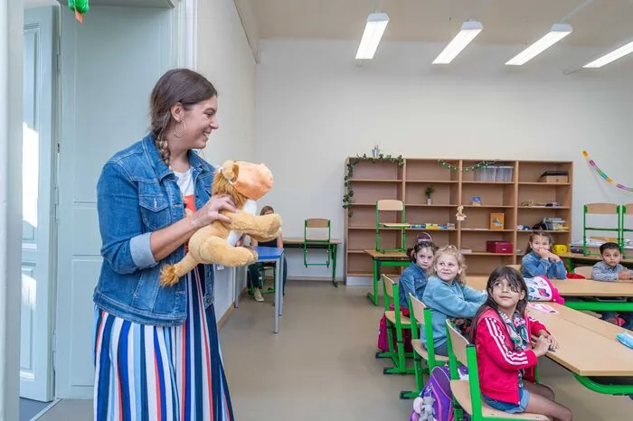 Die Klassenlehrerin zeigt den Erstklässlern ihr Maskottchen: Einen Stofflöwen mit Maske