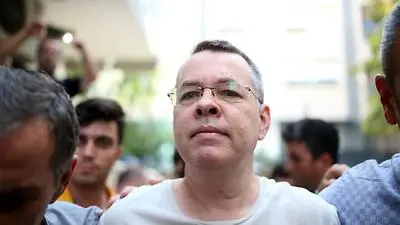 Pastor Andrew Craig Brunson (R), escorted by Turkish plain clothes police officers as he arrives at his house on July 25, 2018 in Izmir. - A Turkish court on July 25, 2018 ruled to place under house arrest an American pastor who has been imprisoned for almost two years on terror-related charges in a case that has raised tensions with the United States, state media said. The state-run Anadolu news agency said he was being put under house arrest, although it was not clear if he had already left prison. (Photo by STRINGER / AFP)