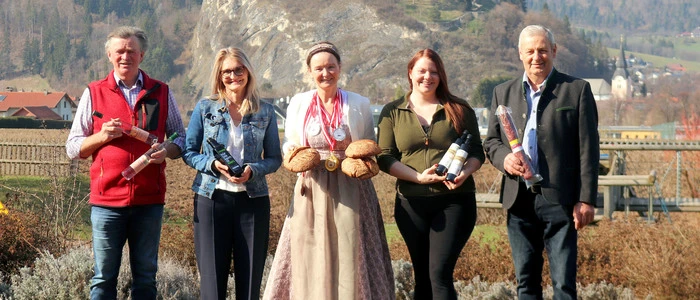 Vier Personen mit Produkten vor Burgruine