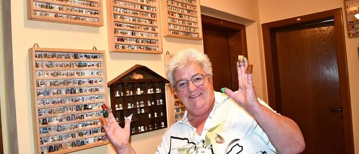 Hermine Gratzer vor einem Teil ihrer mit Fingerhüten bestückten Setzkästen an der Wand