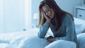 Depressed woman awake in the night, she is touching her forehead and suffering from insomnia