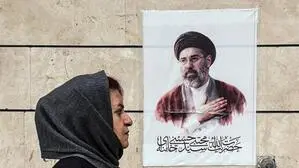Eine iranische Frau mit Kopftuch spaziert an einem Bild vorbei, das den neuen obersten Führer Mojtaba Khamenei zeigt.