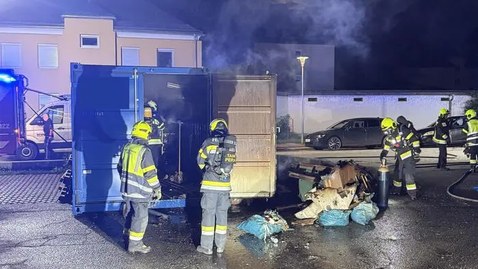 Feuerwehrleute vor einem rauchenden Container | In dem Container war eine Sauerstoffflasche gelagert, die geborgen und gekühlt wurde