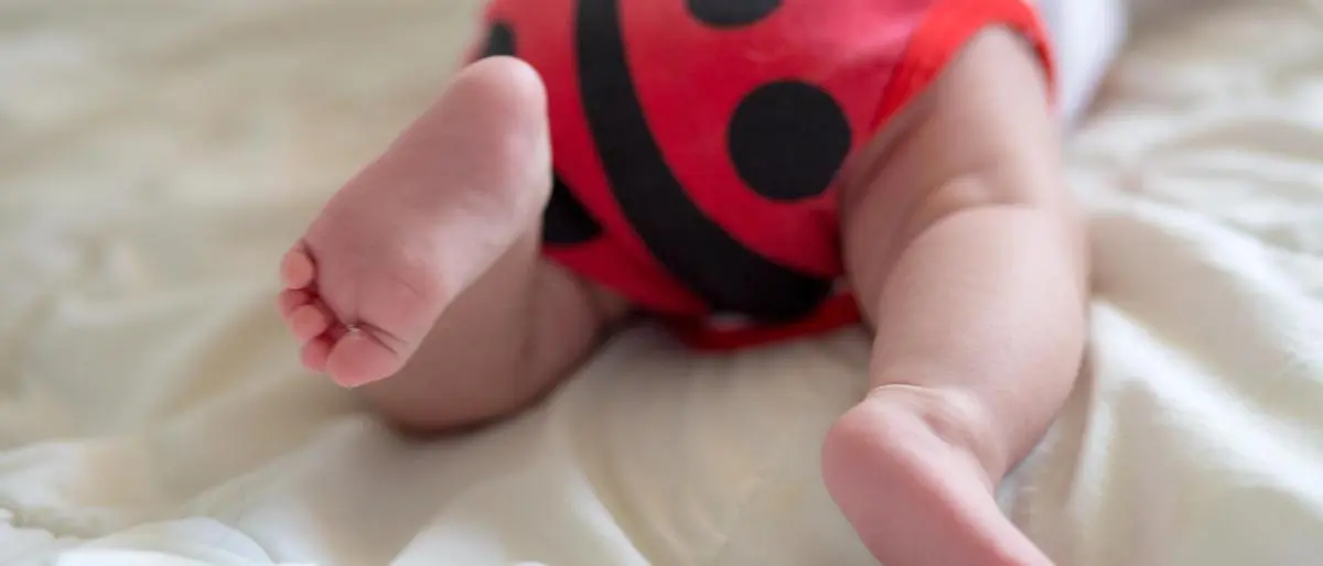 Booty baby in body in form ladybug. newborn baby is lying on belly. Baby is trying to crawl. Baby from the back.