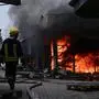 A firefighter works with colleagues to control flames at the central market of Sloviansk on July 5, 2022, following a suspected missile attack amid the Russian invasion of Ukraine. (Photo by MIGUEL MEDINA / AFP)