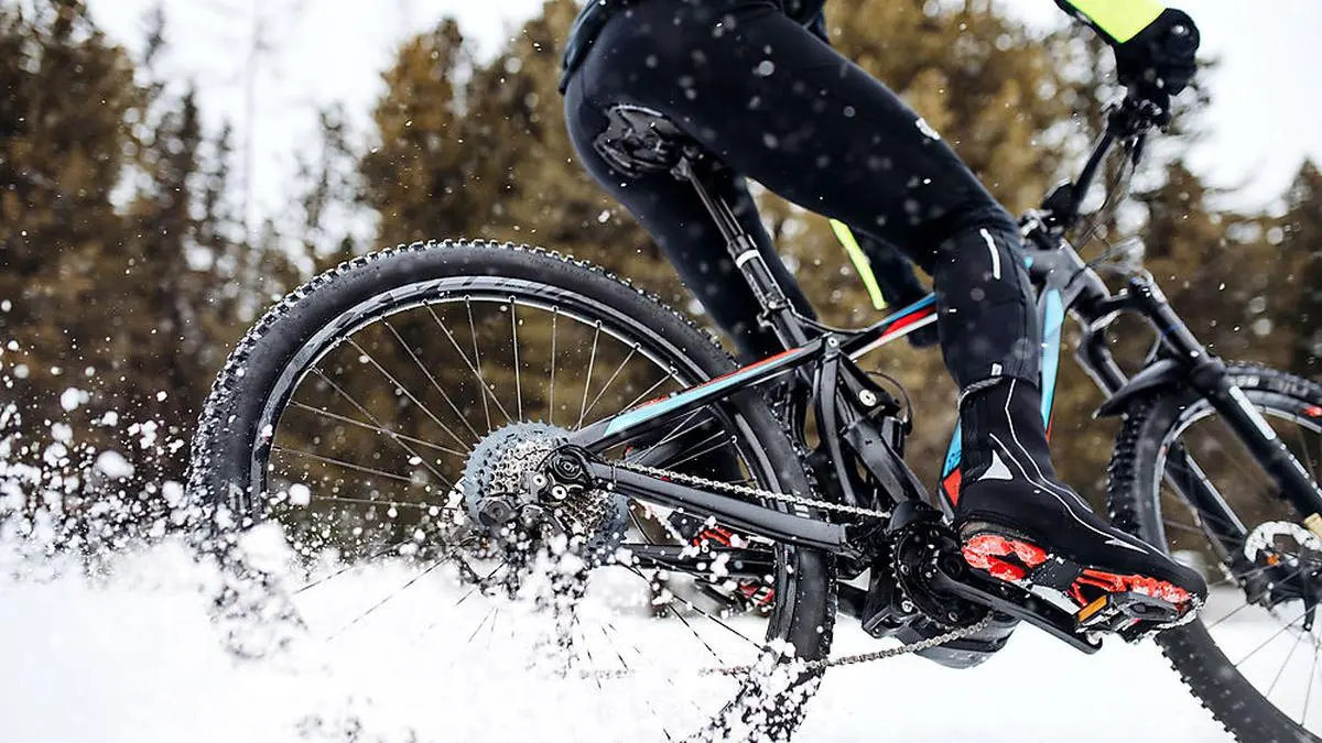 A midsection of mountain biker riding in snow outdoors in winter.