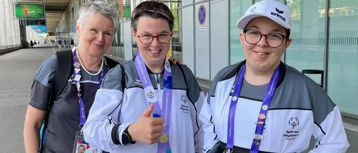 Drei Frauen in Sportoutfit lachen in die Kamera