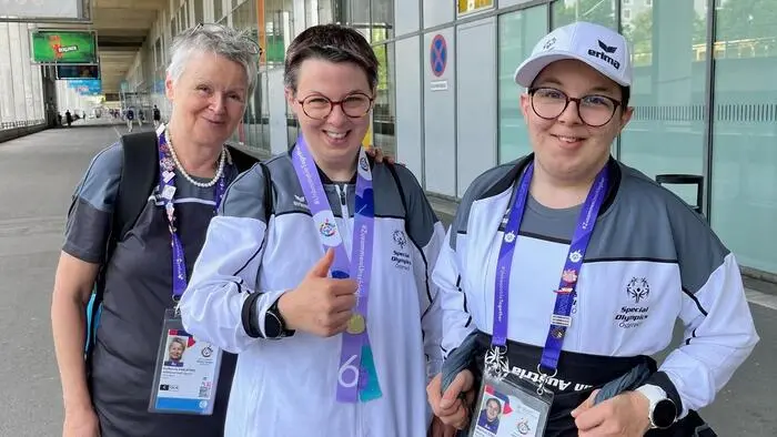 Drei Frauen in Sportoutfit lachen in die Kamera