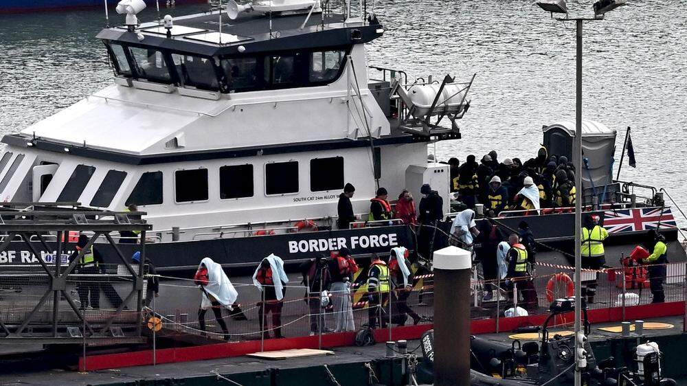 Migranten werden in der südenglischen Stadt Dover von der britischen Grenzbehörde an Land begleitet. Wenn es nach der britischen Regierung geht, könnten sie aber schon bald wieder auf einem Schiff sein