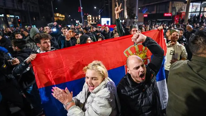 Feiernde Menschen mit einer Serbienflagge