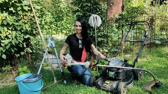 Eine Frau kniet in einem Garten und hat um sich Utensilien für die Gartenpflege und Reinigung liegen