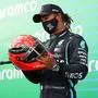 Winner Mercedes' British driver Lewis Hamilton holds the red helmet of former German Formula one champion Michael Schumacher that was offered to him by Mick Schumacher (unseen) on the podium after the German Formula One Eifel Grand Prix at the Nuerburgring circuit in Nuerburg, western Germany, on October 11, 2020. - Lewis Hamilton equalled Michael Schumacher's record of 91 Formula One wins on on October 11, 2020 when he guided his Mercedes to a narrow, if measured, victory at Eifel Grand Prix. Schumacher's 21-year-old son Mick, a rising star and leader of the F2 series, presented Hamilton  with a red helmet from his father's career collection. (Photo by Bryn Lennon / POOL / AFP)
