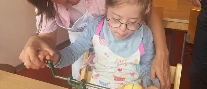 Eine Lehrerin schält mit einem Kind einen Apfel