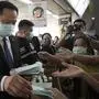 Thailand's Public Health Minister Anutin Charnvirakul, left, distributes masks to commuters during a campaign for wearing masks and washing hands at the skytrain station in Bangkok, Thailand, Friday, Feb. 7, 2020. The coronavirus outbreak in China has thrown Thailand’s and other Asian countries’ travel industry into chaos, threatening billions in losses as millions of would-be travelers are staying home. (AP Photo/Sakchai Lalit)