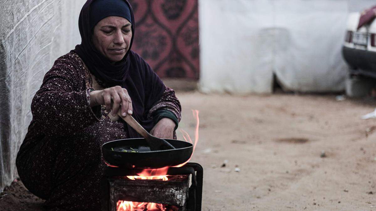 Vertriebene Palästinenser kochen vor ihren Zelten in der Nähe des Shuhada al-Aqsa-Krankenhauses in Deir al-Balah, im mittleren Teil des Gazastreifens.