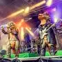 Die Band auf der Bühne: Alle sind als Dinosaurier verkleidet und haben E-Gitarren und Mikrofon in der Hand