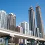 Zu sehen ist die Skyline des Finanzzentrums von Dubai, der größten Stadt der Vereinigten Arabischen Emirate, mit seinen modernen Wolkenkratzern. Im Vordergrund führt eine Hochtrasse der Dubai Metro die Sheikh Zayed Road entlang.  | Blick auf die Skyline des Finanzzentrums von Dubai, der größten Stadt der Vereinigten Arabischen Emirate, mit seinen modernen Wolkenkratzern