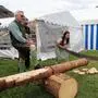 Zwei Frauen in Tracht sägen einen Stamm durch.