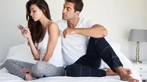 Dude peering over girlfriend's shoulder as she texts