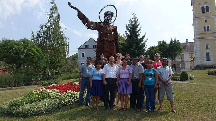 Die Gäste mit beteiligten Unternehmern, Anton Gangl und Pfarrerin Marianne Wagner (6.v.l.) vor der Statue in Tieschen – gebaut von Fernando Crespo (4.v.r.). Francisco Fernandez (1.v.r.) wird in der Region ein Praktikum machen VG