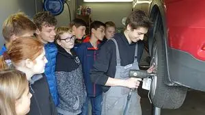 Lehrling Oliver Wahlhütter zeigt den Schülern, wie man einen Autoreifen fachgerecht  wechselt