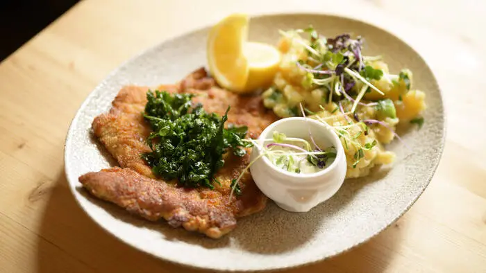 Paniertes Schnitzel mit Kartoffelsalat auf einem weißen Teller.