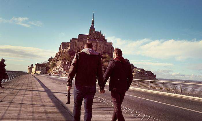 Das urbane Milieu trifft das ländliche Frankreich: Männliches Paar vor dem Mont-Saint-Michel in der Normandie