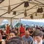 Blick in ein Kirchtagszelt, das gut gefüllt ist, im Hintergrund sieht man die Villacher Innenstadt