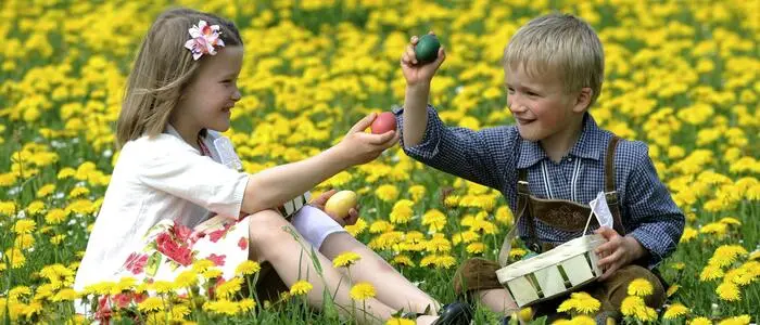 Zwei Kinder in Blumenwiese mit Ostereiern in der Hand
