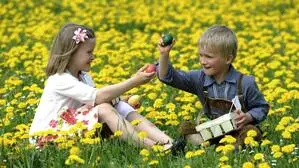 Zwei Kinder in Blumenwiese mit Ostereiern in der Hand