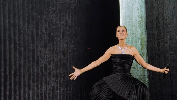 Céline Dion in einem schwarzen Kleid mit ausgestreckten Armen