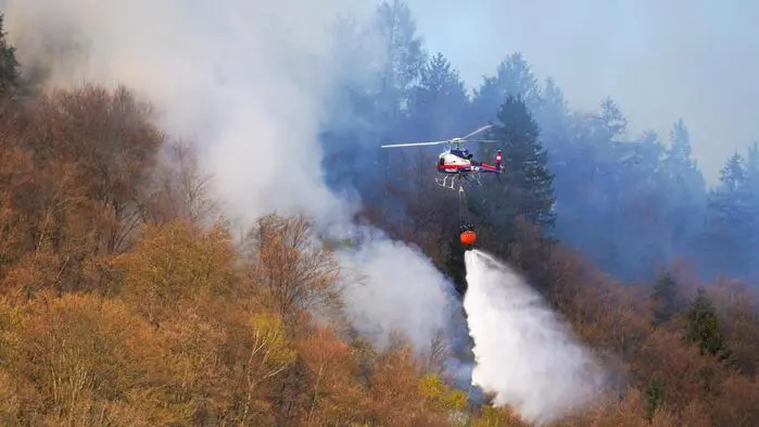 Ein Löschhubschrauber über einem rauchenden Wald