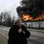 (FILES) A woman reacts as she stands in front of a house burning after being shelled in the city of Irpin, outside Kyiv, on March 4, 2022. More than 1.2 million people have fled Ukraine into neighbouring countries since Russia launched its full-scale invasion on February 24, United Nations figures showed on March 4, 2022. (Photo by Aris Messinis / AFP)