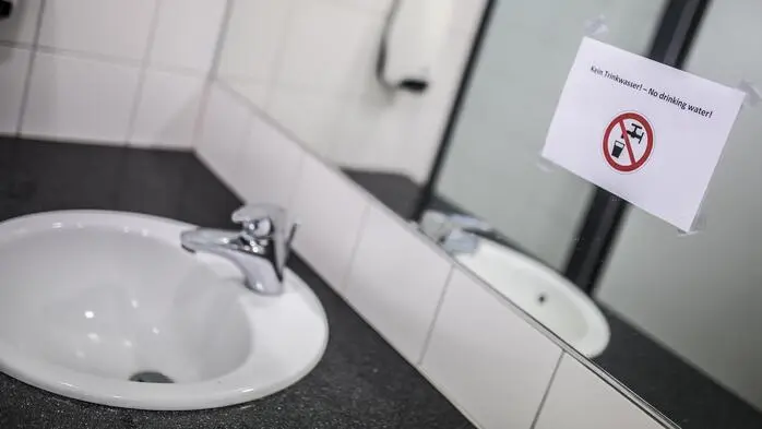 Ein Waschbecken und ein Spiegel. Auf dem Spiegel ist ein Stück Papier, das darauf hinweist, dass man das Wasser nicht trinken kann