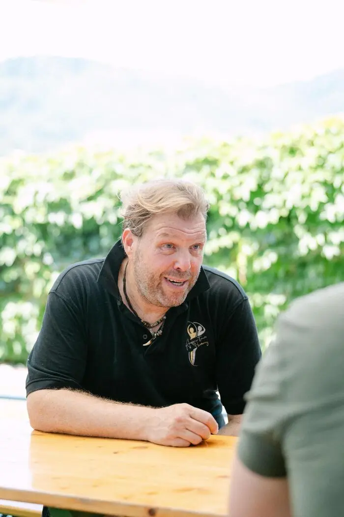 Andreas Peissel sitzt auf einer Bierbank im Außenbereich der Auster und ist in sein Gespräch vertieft