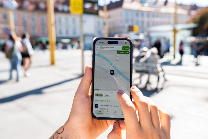 Nach einem gemütlichen Espresso bei einem der Stand‘ln auf dem Jakominiplatz, plant Klara mit der GrazMobil-App ihre nächste Route
