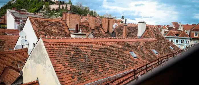 Dachlandschaft der Grazer Altstadt mit Uhrturm im Hintergrund