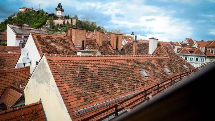 Dachlandschaft der Grazer Altstadt mit Uhrturm im Hintergrund