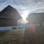 Zwei Häuser, großteils aus Holz, dazwischen eine Wäscheleine in der untergehenden Sonne