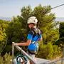 School boy preparing for zipline adventure. Happy active child put safety helmet on head. Summer fun with climbing in mountains