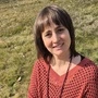 Die Erzählerin Barbara Brunner sitzt auf einer grünen Wiese
