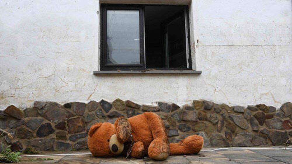 Ein mit Schlamm beschmierter Teddybär vor einem Haus in Schuld.