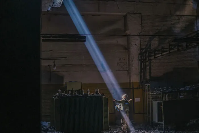 Wie ein Bühnenlicht durchbricht ein Lichtstrahl die Dunkelheit einer Halle.  